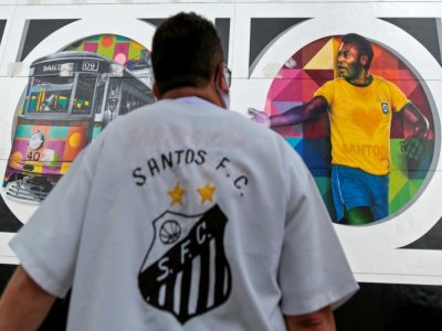 Un supporteur du club brésilien de football de Santos regarde une fresque dessinée par l'artiste brésilien Kobra représentant Pelé, à Santos au Brésil, le 21 octobre 2020 - Miguel SCHINCARIOL [AFP]