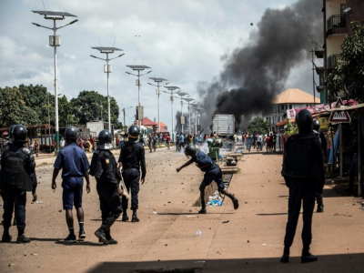 Un policier lance une pierre sur des manifestants à Conakry, le 21 octobre 2020 en Guinée - JOHN WESSELS [AFP]