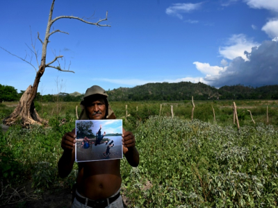 Luis Gutierrez, pêcheur, montre une photo prise à l'endroit il se trouve désormais, sur la rive asséchée du lac Jucutuma, à San Pedro Sula, 240 kilomètres au nord de Tegucigalpa, le 13 octobre 2020 - ORLANDO SIERRA [AFP]