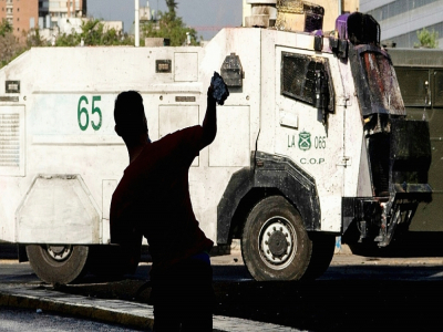 Un protestataire lance une pierre sur un véhicule des forces de l'ordre, à Santiago, le 23 octobre 2020 - MARTIN BERNETTI [AFP]