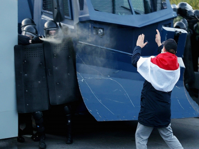 Un manifestant face aux policiers anti-émeute pendant une manifestation à Minsk, le 25 octobre 2020 - Stringer [AFP]