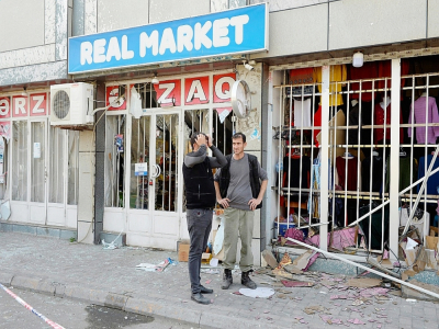 Deux hommes devant un magasin qui a subi des destructions après des tirs de missiles à Barda, le 28 octobre 2020 - TOFIK BABAYEV [AFP]