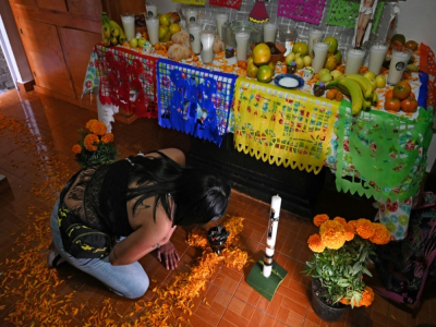 Une femme prépare un autel à la mémoire d'une parente décédée du Covid-19 avant le "Jour des morts", le 25 octobre 2020 à Mexico - RODRIGO ARANGUA [AFP]