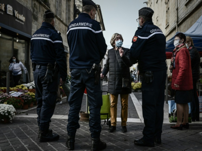 Une femme portant un masque de protection discute avec des gendarmes à l'entrée d'un marché à Libourne, le 30 octobre 2020 - Philippe LOPEZ [AFP]