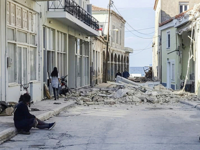 Des habitants près d'une maison détruite par un séisme sur l'île de Samos (Grèce), le 30 octobre 2020 - STR [Eurokinissi/AFP]