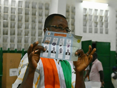 Un membre de la Commission électorale ivoirienne montre un bulletin de vote pendant le comptage des voix, le 31 octobre 2020 à Abidjan - Issouf SANOGO [AFP]