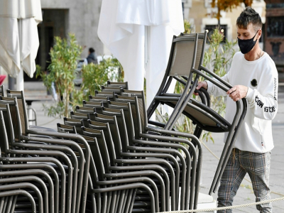Le propriétaire d'un café de Stuttgart en Allemagne empile les chaises en raison de la fermeture de son établissement le 2 novembre 2020 - THOMAS KIENZLE [AFP]