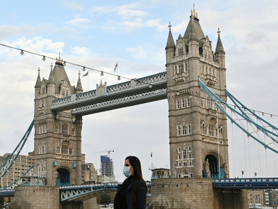 Une femme portant un masque traverse le Tower Bridge à Londres le 1er novembre 2020 alors que l'Angleterre se prépare à de nouvelles restrictions - JUSTIN TALLIS [AFP]