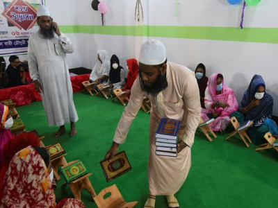 Un enseignant distribue des copies du Coran dans une madrasa pour les personnes transgenres, à Dacca le 6 novembre 2020 - Munir UZ ZAMAN [AFP]