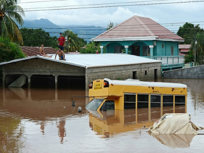 Des habitants réfugiés sur le toit d'un bâtiment près d'un bus submergé par les eaux, le 6 novembre 2020 à El Progreso, au Honduras - Orlando SIERRA [AFP]