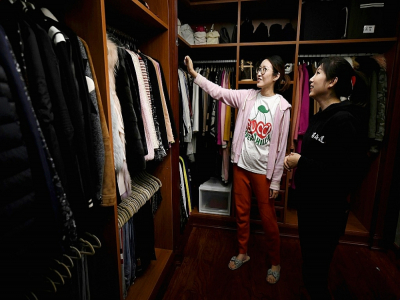 Chen Rui (g) découvre sa garde-robe réorganisée par des experts du rangement, le 26 octobre 2020 à Pékin - NOEL CELIS [AFP]