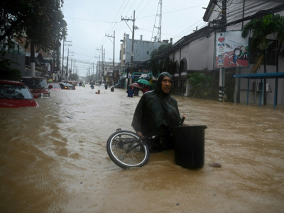 Un habitant porte ses affaires dans une rue inondée de Marikina City, dans la banlieue de Manille le 12 novembre 2020 - Ted ALJIBE [AFP]