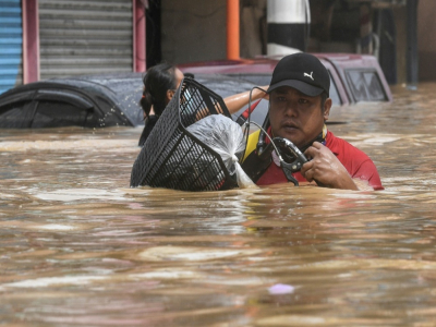 Un habitant porte son vélo en avançant dans une rue inondée après le passage du typhon Vamco, à Marikina City, quartier de Manille, le 12 novembre 2020 - Ted ALJIBE [AFP]