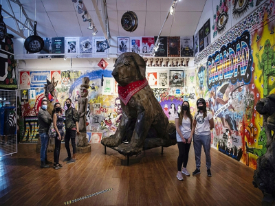 Des visiteurs du musée du "Soulèvement social" à Santiago admirent le 11 novembre 2020 une sculpture géante d'un chien noir au foulard rouge devenu la mascotte des manifestations sociales d'octobre 2019 au Chili - MARTIN BERNETTI [AFP]