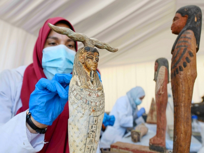 Une archéologue nettoie des statuettes en bois découvertes à Saqqara, lors d'une cérémonie, le 14 novembre 2020 - Ahmed HASAN [AFP]