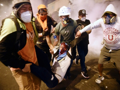 Des manifestants portent un blessé lors de heurts avec la police au cours d'un rassemblement de soutien au président Vizcarra, le 14 novembre 2020 à Lima, au Pérou - ERNESTO BENAVIDES [AFP]