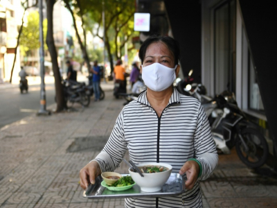 Une serveuse apporte un bol de soupe aux nouilles à un client dans une rue de Ho Chi Minh-Ville, le 8 septembre 2020 au Vietnam - Nhac NGUYEN [AFP]