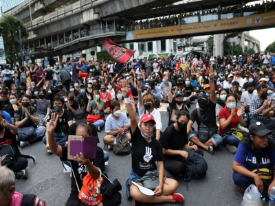 Des manifestants rassemblés à un important croisement à Bangkok font le salut à trois doigts, signe de ralliement du mouvement de protestation, le 18 novembre 2020 - Jack TAYLOR [AFP]