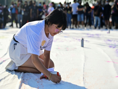 Benjamaporn "Ploy" Nivas écrit des messages sur une toile blanche lors d'une manifestation à Bangkok le 14 novembre 2020 - Lillian SUWANRUMPHA [AFP]