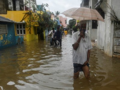 Des habitants de Pondichéry pataugent dans une rue inondée après de fortes pluies liées au cyclone Nivar, le 26 novembre 2020 - Arun SANKAR [AFP]