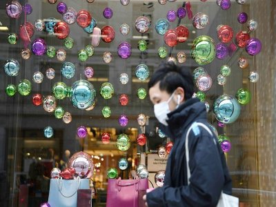 Un passant masqué devant la vitrine décorée pour Noël d'un magasin fermé pour cause de virus à Londres le 26 novembre 2020 - DANIEL LEAL-OLIVAS [AFP]