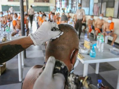 Un détenu, expert en l'art du tatouage, recouvre d'une croix noire le tatouage d'un codétenu qui marque l'appartenance d'un détenu à un gang, le 23 novembre 2020 à la prison de New Bilibid, à Manille, aux Philippines - Jam STA ROSA [AFP]