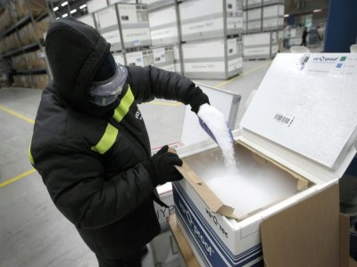 Un employé de l'entreprise allemande Va-Q-Tech remplit de glace sèche des conteneurs habillés de carton, le 1er décembre 2020 à Wurzburg - Daniel ROLAND [AFP]