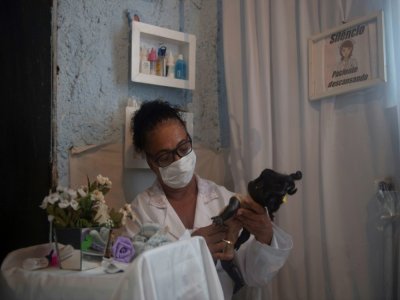 Suelen da Silva vérifie une des poupées qui lui a été confiée pour être "soignée" dans son hôpital de poupées, à Niteroi près de Rio de Janeiro, le 10 décembre 2020 - MAURO PIMENTEL [AFP]