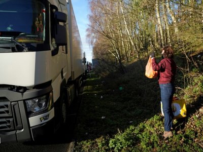 Uen femme distribue des vivres à des routiers immobilisés sur l'autoroute M20 conduisant au port de Douvres, le 25 décembre 2020 à Ashford - Niklas HALLE'N [AFP]