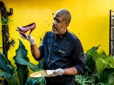 Le maître-chocolatier et entrepreneur Ralph Leroy pose avec l'une de ses plus emblématiques créations, la sculpture d'un escarpin, dans les ateliers de la chocolaterie Makaya de Petionville (Haïti) le 23 décembre 2020 - Valerie Baeriswyl [AFP]