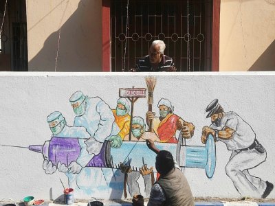 Des artistes terminent une peinture murale représentant des soignants portant le vaccin contre le virus à Kolkata le 2 janvier 2021 - Dibyangshu SARKAR [AFP]
