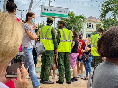 Des policiers cubains surveillent la file d'attente devant une banque de La Havane, le 4 janvier 2021 - ADALBERTO ROQUE [AFP]