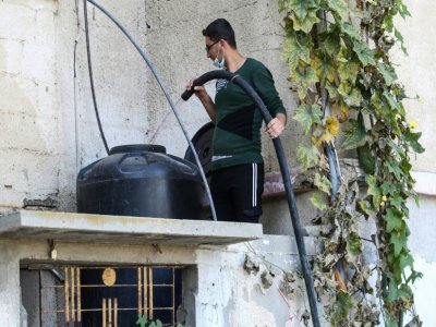 Un Palestinien remplit son réservoir d'eau potable achetée auprès d'une société, à Khan Younès (Gaza) le 18 novembre 2020 - SAID KHATIB [AFP]