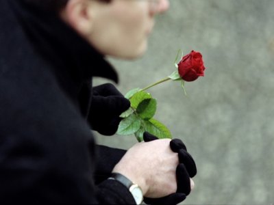 Un homme tient une rose devant l'église de Jarnac lors des funérailles de l'ancien président François Mitterrand, le 11 janvier 1996 - JOEL ROBINE [AFP/Archives]