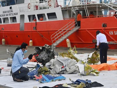 Des membres de la Commission de sécurité des transports inspectent des débris du Boeing accidenté, sur le port de Jakarta, le 12 janvier 2021 - ADEK BERRY [AFP]