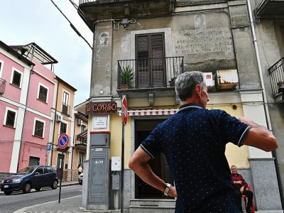 Un homme se tient devant une maison de l'époque fasciste, avec des écrits et des dessins représentant le défunt leader fasciste italien Benito Mussolini, dans la rue du vieux centre de la ville de Cinquefrondi, dans la région de Calabre, au sud de l' - Andreas SOLARO [AFP]