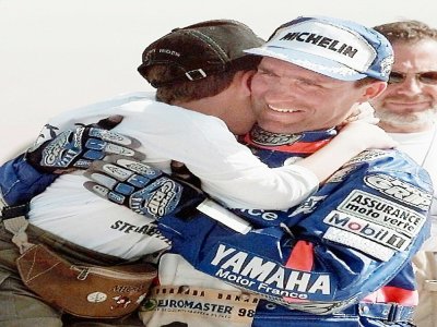 le pilote français Stéphane Peterhansel (Yamaha), vainqueur du 20e rallye-raid Paris-Dakar dans la catégorie motos, embrasse son fils Nicolas, le 18 janvier 1998 à Dakar, à l'issue de la 17e et dernière étape, disputée entre Saint-Louis et Dakar - Eric CABANIS [AFP/Archives]