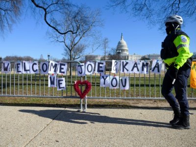 un policier passe devant une banderole souhaitant la bienvenue à la future vice-président Kamala Harris près du Capitole le 10 janvier 2021 - Andrew CABALLERO-REYNOLDS [AFP]