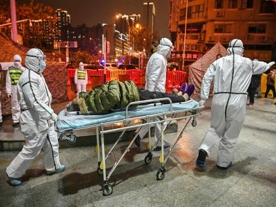 Des personnels médicaux transportent un patient présentant des symptômes du coronavirus à l'hôpital de la Croix-Rouge, le 25 janvier 2020 à Wuhan, en Chine - Hector RETAMAL [AFP/Archives]