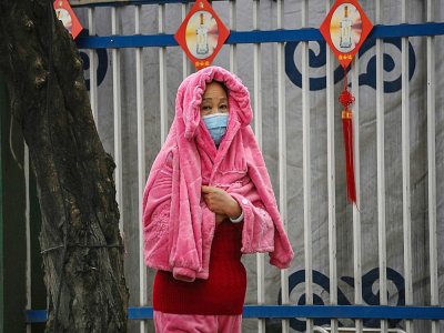Une femme se couvre de la pluie devant le centre communautaire de Jiangxinyuan où les membres de l'équipe de l'Organisation mondiale de la santé (OMS) qui enquête sur les origines du coronavirus COVID-19 se rendent à Wuhan, dans la province centrale - Hector RETAMAL [AFP]