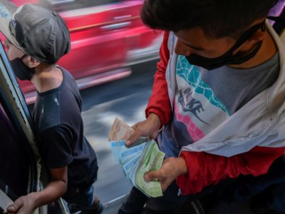 Un vendeur de tickets compte sa recette dans un autobus à Caracas, le 29 janvier 2021 - Federico PARRA [AFP]