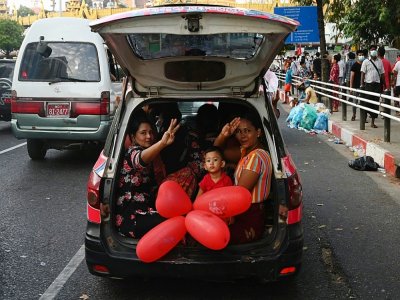 Une femme assise à l'arrière d'une voiture fait le salut à trois doigts, en signe de résistance, à Rangoun le 7 février 2021 - STR [AFP]