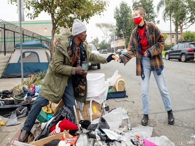 Un volontaire distribue de l'aide à un SDF le 8 février 2021 à Hollywood (Etats-Unis) - VALERIE MACON [AFP]