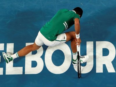 Le Serbe Novak Djokovic tombe en tentant de frapper un retour contre l'Américain Taylor Fritz au 3e tour de l'Open d'Australie, à Melbourne, le 12 février 2021 - Brandon MALONE [AFP]