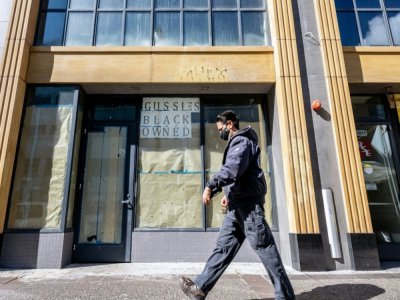 Une personne passe devant un magasin fermé sur la devanture duquel on peut lire "Propriétaire noir", à Oakland, en Californie, le 12 février 2021 - JOSH EDELSON [AFP]