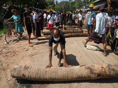 Près de la gare centrale à Rangoun, capitale économique de la Birmanie, des habitants bloquent une rue à l'aide de troncs d'arbres pour empêcher la police de pénétrer dans le quartier, le 14 février 2021 - Sai Aung Main [AFP]