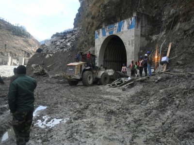 Un bulldozer et des équipes de secours à l'entrée d'un tunnel bloqué par de la boue et des débris pendant les opérations de sauvetage à Tapovan, le 9 février 2021 en Inde - Sajjad HUSSAIN [AFP/Archives]