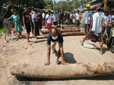 Près de la gare centrale à Rangoun, capitale économique de la Birmanie, des habitants bloquent une rue à l'aide de troncs d'arbres pour empêcher la police de pénétrer dans le quartier, le 14 février 2021 - Sai Aung Main [AFP]