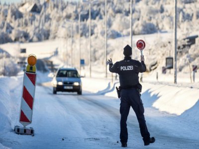 Un policier fédéral allemand arrête un véhicule pour un contrôle à un poste frontière avec l'Autriche le 14 février 2021 près de Zinnwald. - Odd ANDERSEN [AFP]