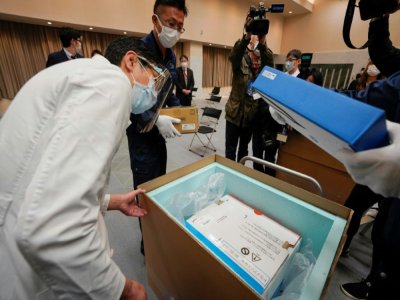 Un membre du personnel médical vérifie la température de conservation des doses du vaccin Pfizer contre le coronavirus livrées dans un hôpital de Tokyo, le 16 février 2021 - Kimimasa MAYAMA [POOL/AFP]